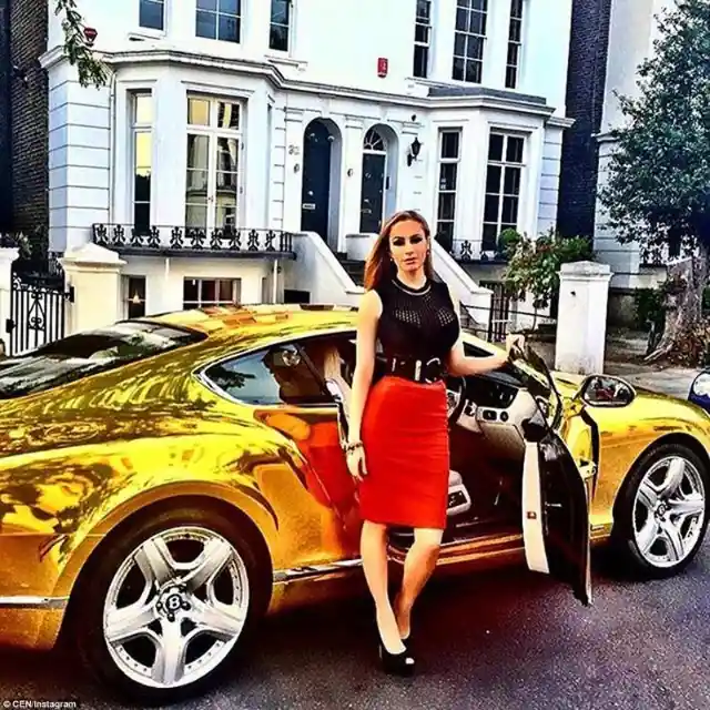 A spectacularly-coated golden sports car outside of a beautiful home