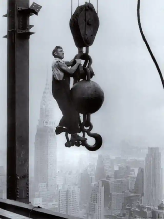 13. An Empire State builder hanging on a crane above New York City, 1925.