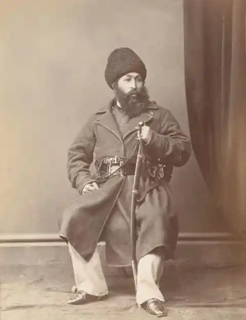 Sher Ali Khan poses wearing a plain overcoat and distinctive fur hat