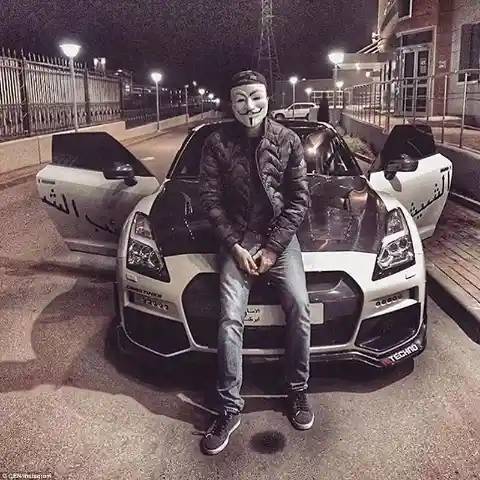 This teen wearing a mask sits on the bonnest of his expensive sports cars