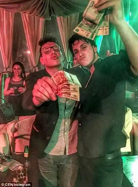 Showing off money, two kids pose inside a nightclub